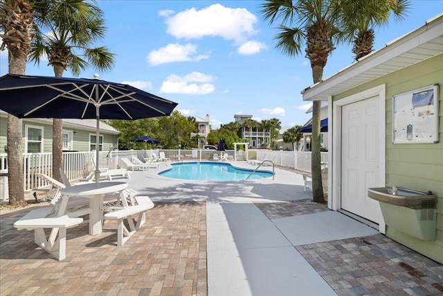 community pool with fence and a patio