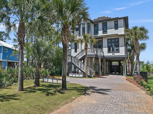 182 My Way, Santa Rosa Beach, FL 32459 - coastal home with a carport, decorative driveway, fence, a front lawn, and stairs