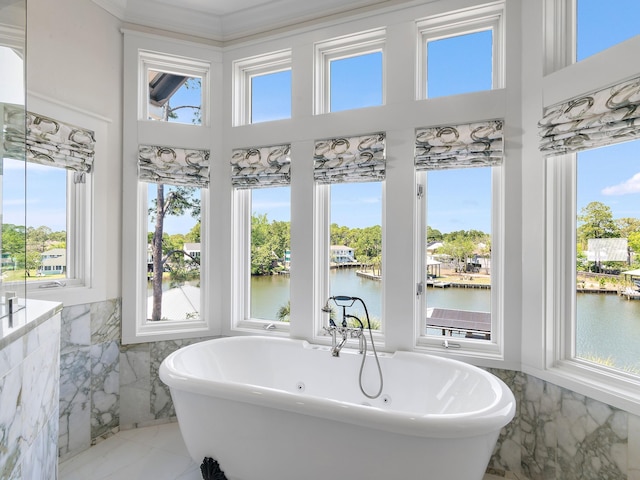182 My Way, Santa Rosa Beach, FL 32459 - bathroom featuring wainscoting, a freestanding tub, tile walls, a towering ceiling, and a water view