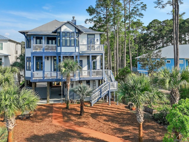 182 My Way, Santa Rosa Beach, FL 32459 - view of front of home featuring stairs, a chimney, a balcony, covered porch, and metal roof