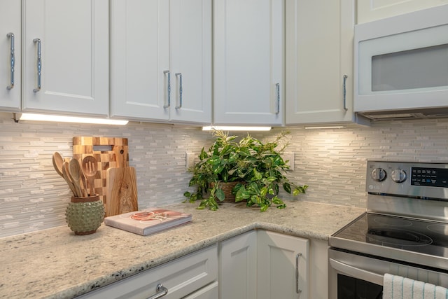17545 Front Beach Rd Unit 1507, Panama City Beach, FL 32413 - kitchen with electric stove, white microwave, backsplash, and white cabinetry