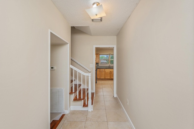 11 Birch Ave, Shalimar, FL 32579 - hallway with light tile patterned floors, a textured ceiling, a sink, visible vents, and stairs