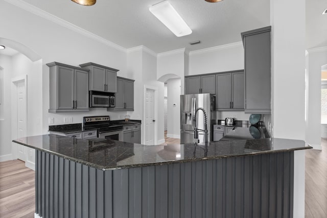 129 Red Maple Way, Niceville, FL 32578 - kitchen featuring stainless steel appliances, arched walkways, a peninsula, gray cabinets, and dark stone counters
