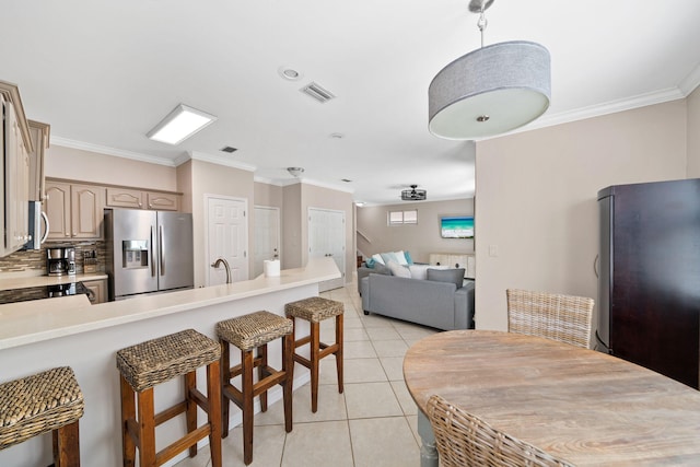 229 Inverrary Dr, Destin, FL 32541 - kitchen with visible vents, a peninsula, a kitchen breakfast bar, light tile patterned floors, and stainless steel appliances