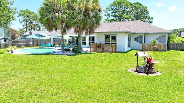 back of house featuring a fenced backyard, stucco siding, a shingled roof, a fenced in pool, and a lawn