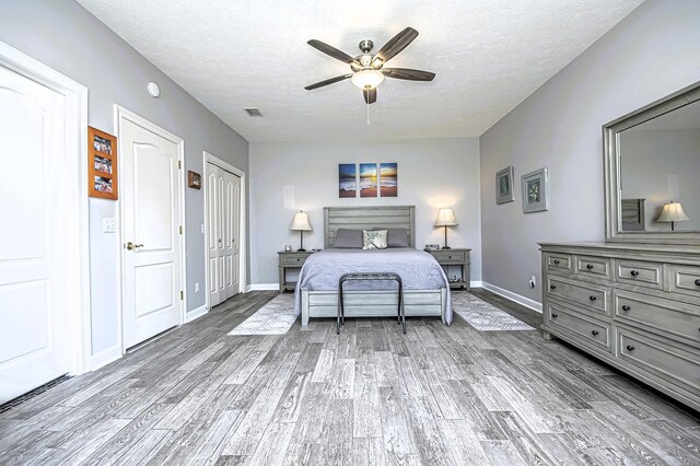 bedroom featuring a textured ceiling, wood finished floors, visible vents, and baseboards
