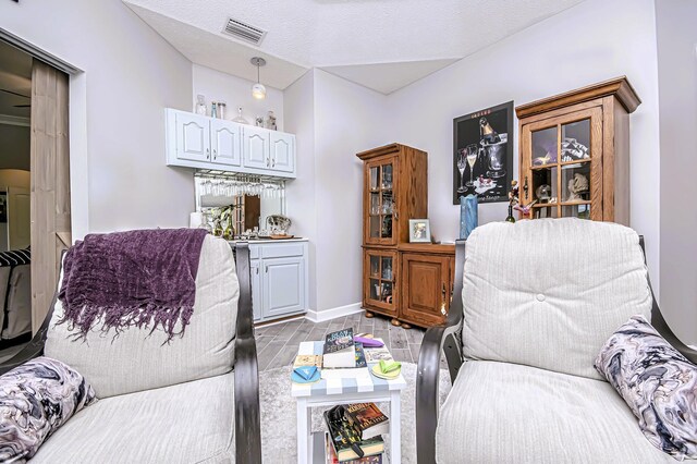living room with visible vents, bar area, and baseboards