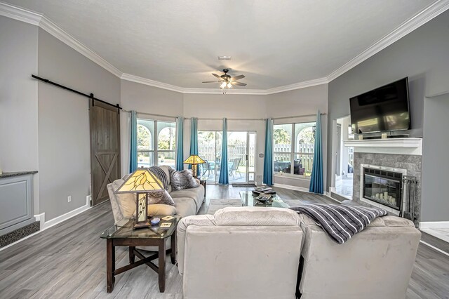 living room with baseboards, a barn door, ceiling fan, and crown molding