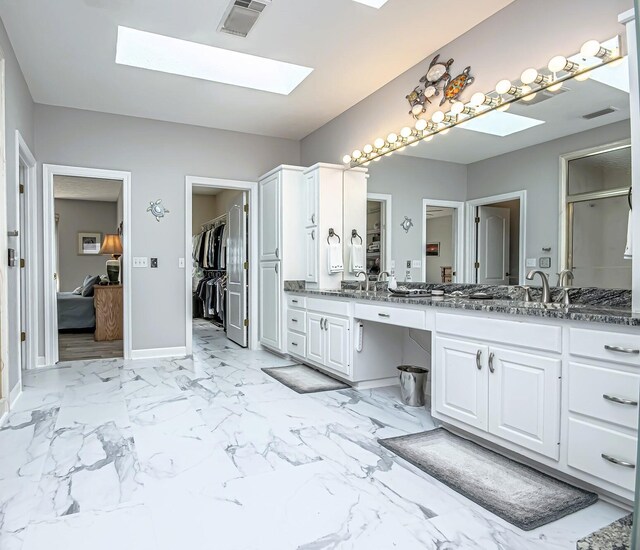 full bath with visible vents, vanity, baseboards, and a skylight