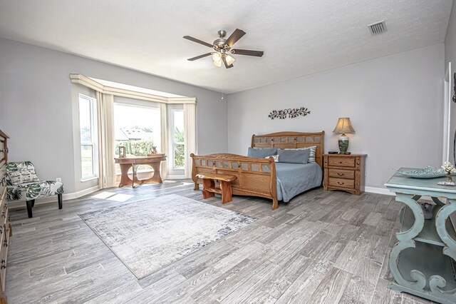 bedroom with baseboards, visible vents, wood finished floors, and a ceiling fan