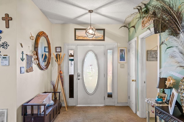 carpeted foyer with a textured ceiling and visible vents