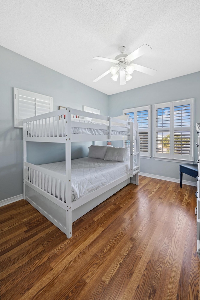 bedroom with a textured ceiling, wood finished floors, ceiling fan, and baseboards