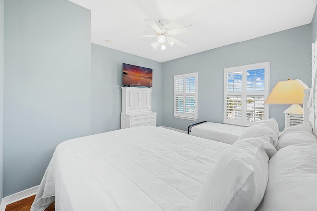 bedroom with baseboards, a ceiling fan, and dark wood-style flooring