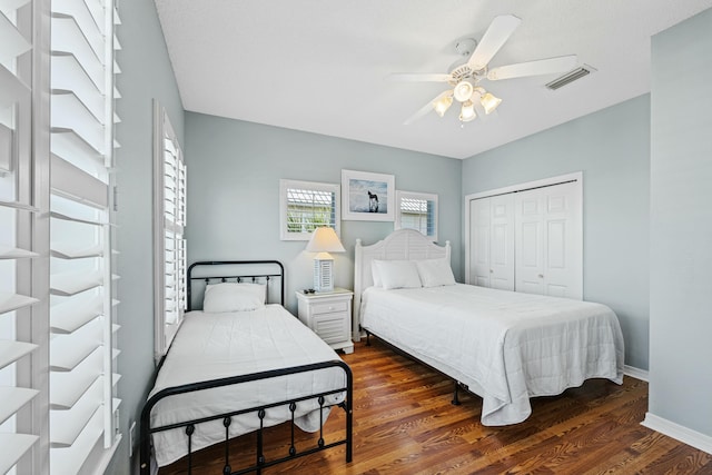 bedroom with a closet, ceiling fan, visible vents, baseboards, and wood finished floors