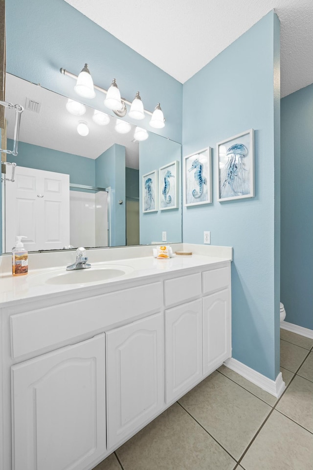 full bath featuring an enclosed shower, vanity, tile patterned flooring, and baseboards
