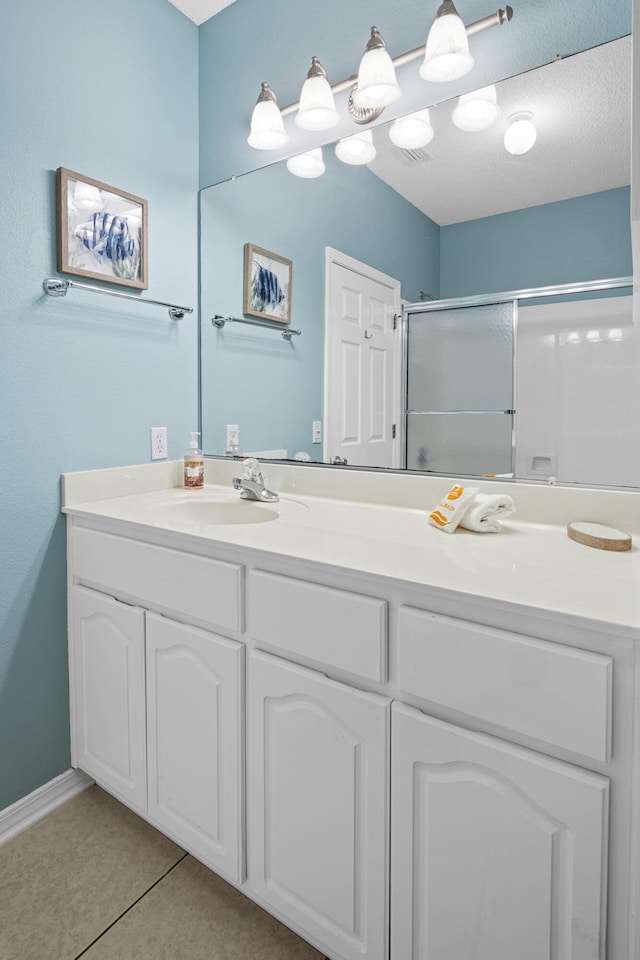full bath with double vanity, a sink, a shower stall, and tile patterned floors