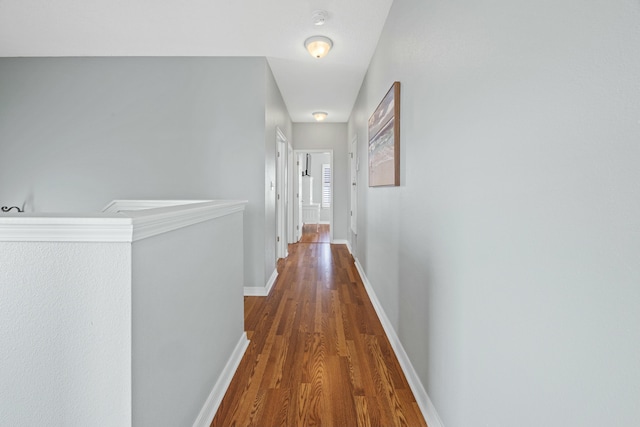 hallway featuring an upstairs landing, wood finished floors, and baseboards