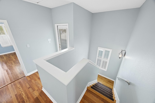 staircase with baseboards, wood finished floors, and attic access