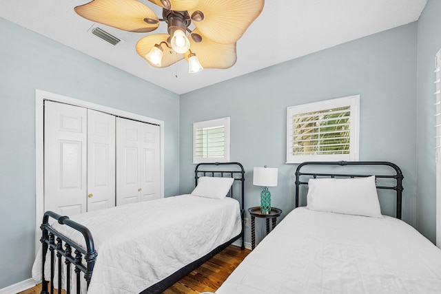bedroom featuring baseboards, a closet, dark wood-style floors, visible vents, and a ceiling fan