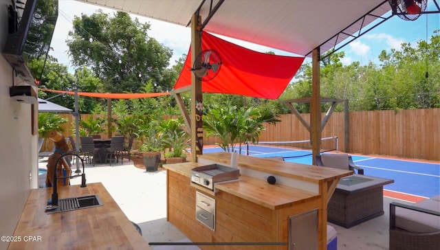 view of patio / terrace with a fenced backyard, a sink, area for grilling, and outdoor dining space