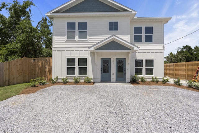 view of front of property with board and batten siding, fence, and driveway