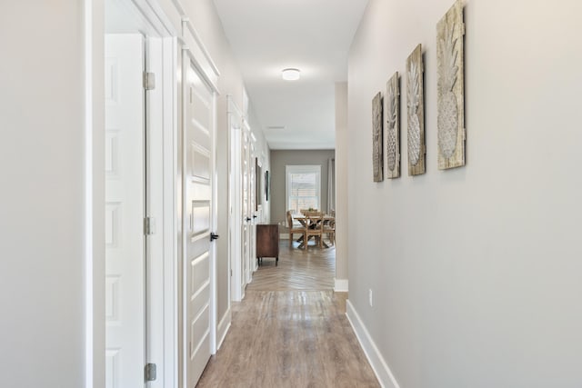 hall with baseboards and light wood finished floors