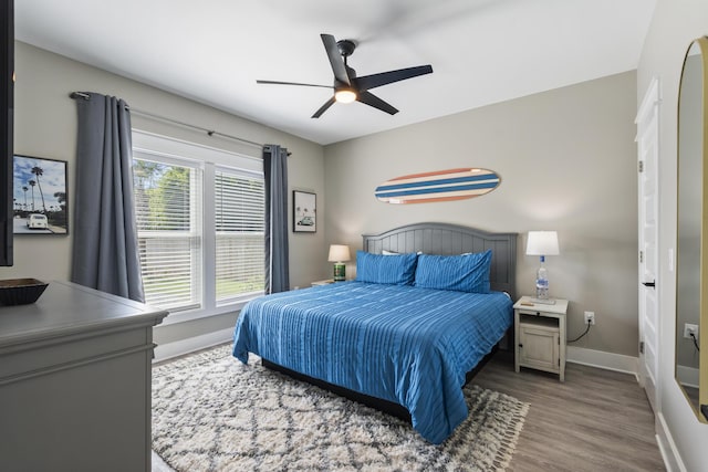 bedroom featuring a ceiling fan, baseboards, and wood finished floors