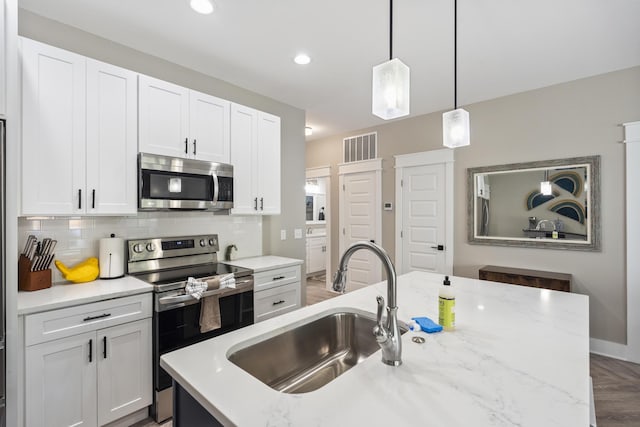kitchen featuring visible vents, white cabinetry, tasteful backsplash, a sink, and appliances with stainless steel finishes