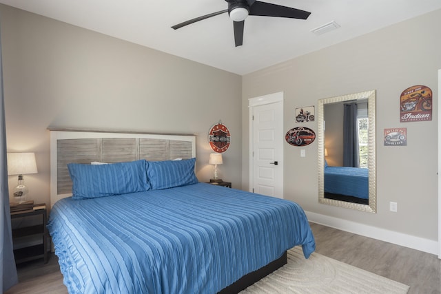 bedroom featuring baseboards, a ceiling fan, wood finished floors, and visible vents