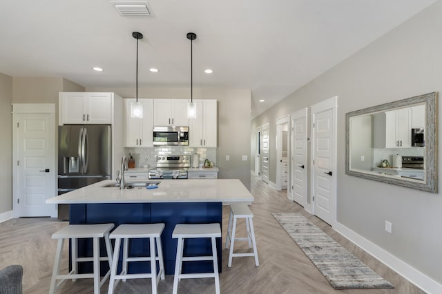 kitchen with a kitchen bar, visible vents, a sink, baseboards, and stainless steel appliances