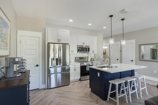 kitchen featuring a kitchen bar, recessed lighting, white cabinets, a sink, and appliances with stainless steel finishes