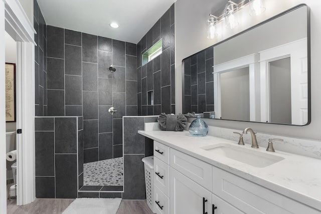 bathroom with vanity, wood finished floors, toilet, recessed lighting, and a walk in shower