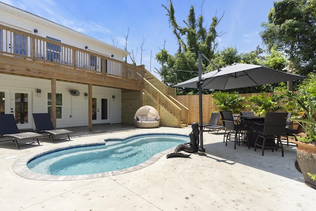 view of swimming pool featuring french doors, a wooden deck, a fenced in pool, fence, and a patio
