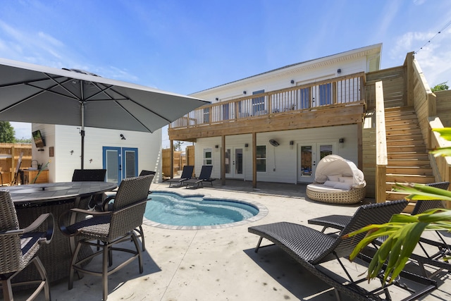 back of property featuring french doors, a deck, a fenced in pool, a patio, and stairs