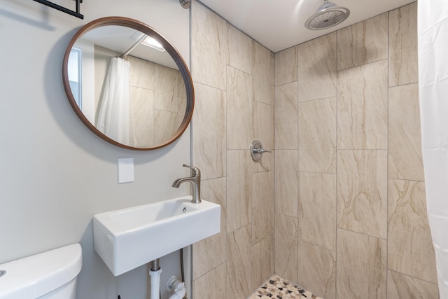 full bathroom featuring a sink, a tile shower, and toilet