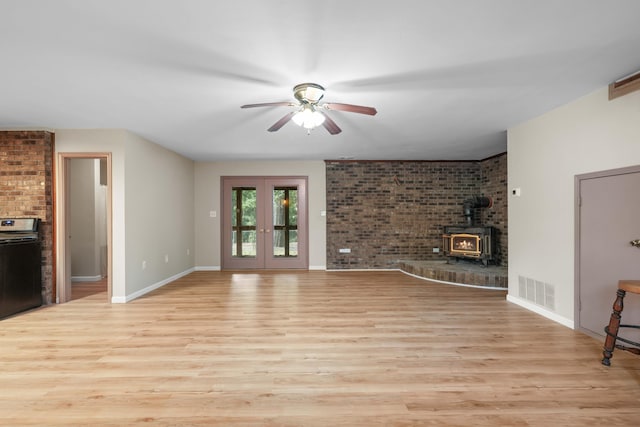 255 Brackin St, Crestview, FL 32539 - unfurnished living room with visible vents, a wood stove, brick wall, light wood-style floors, and a ceiling fan