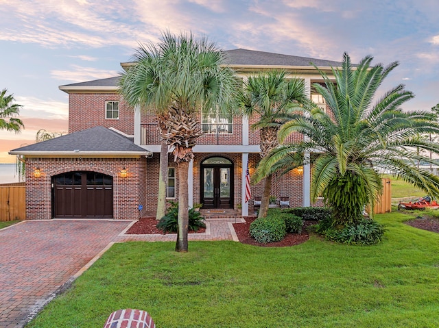 mediterranean / spanish-style house with french doors, a front yard, decorative driveway, and a garage