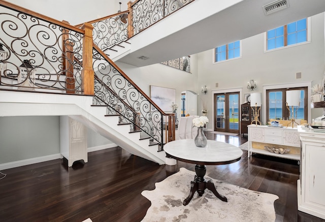 entrance foyer with a high ceiling, stairs, baseboards, dark wood-type flooring, and visible vents