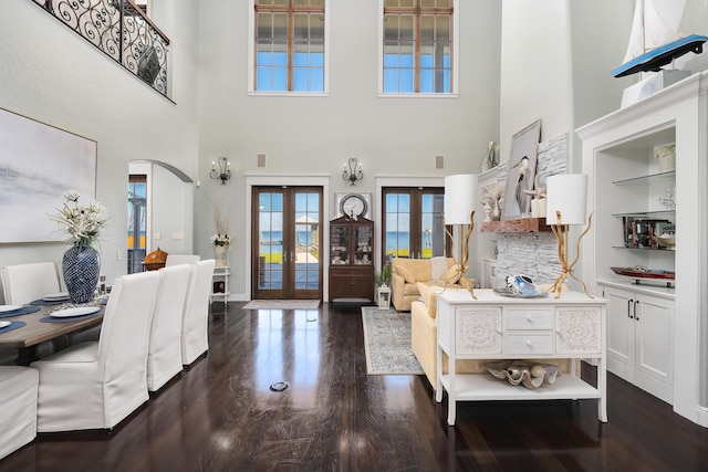 entryway with arched walkways, a high ceiling, french doors, and wood finished floors