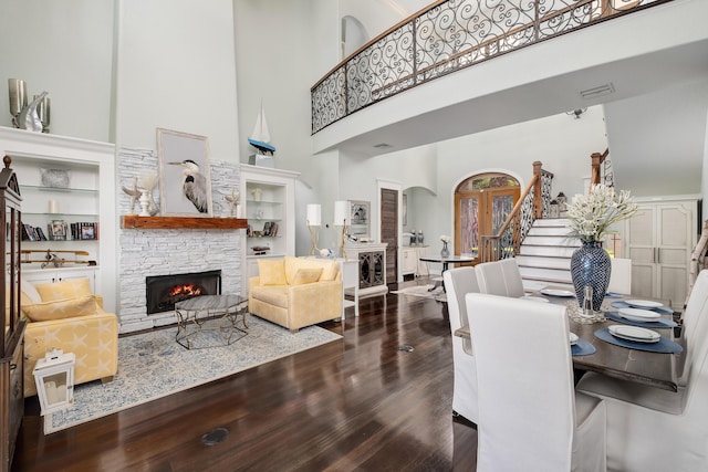 dining space featuring a stone fireplace, arched walkways, stairs, and a towering ceiling