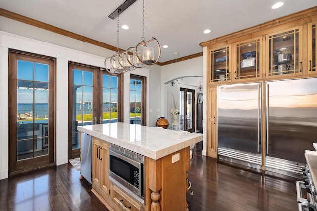 kitchen featuring built in appliances, a center island, a wealth of natural light, and light countertops