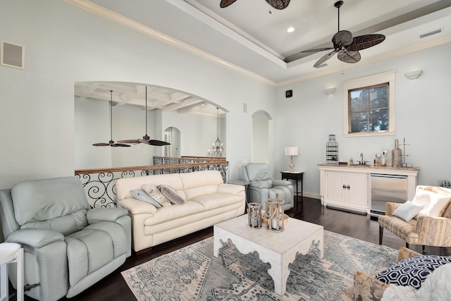 living area with arched walkways, ceiling fan, dark wood-type flooring, and visible vents