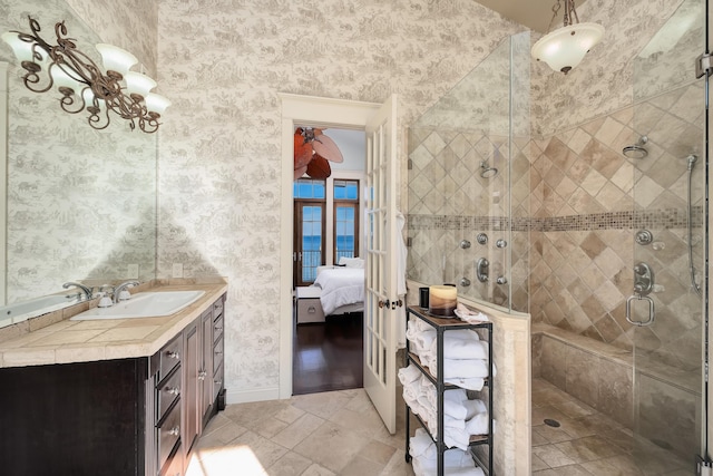 bathroom with vanity, wallpapered walls, a shower stall, french doors, and ensuite bath
