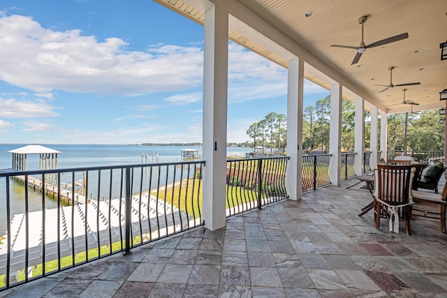 view of patio featuring a ceiling fan, a water view, and a balcony