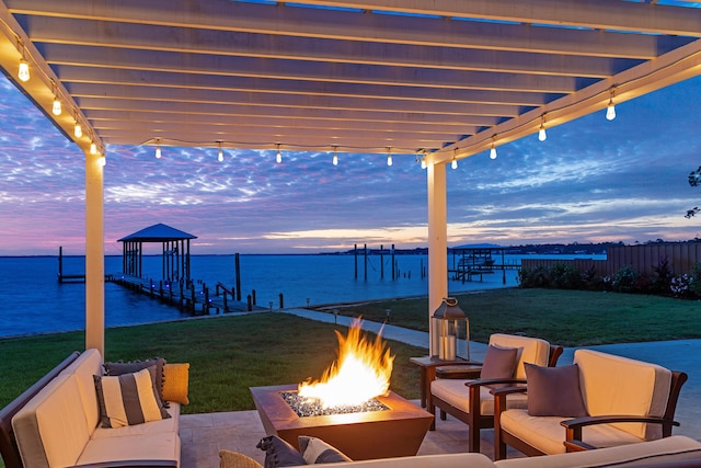 view of patio / terrace featuring boat lift, a dock, a water view, and an outdoor living space with a fire pit