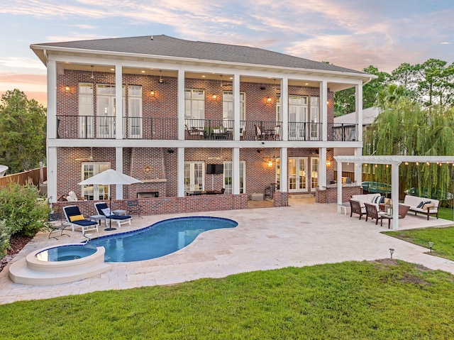 back of house at dusk with a patio, outdoor lounge area, a balcony, and brick siding