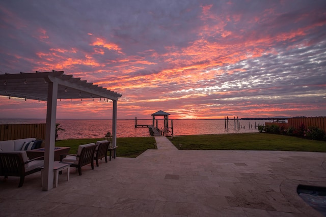 patio terrace at dusk with fence, a pergola, a water view, an outdoor living space, and a lawn
