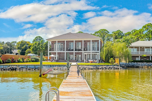 dock area featuring a water view, fence, and a balcony