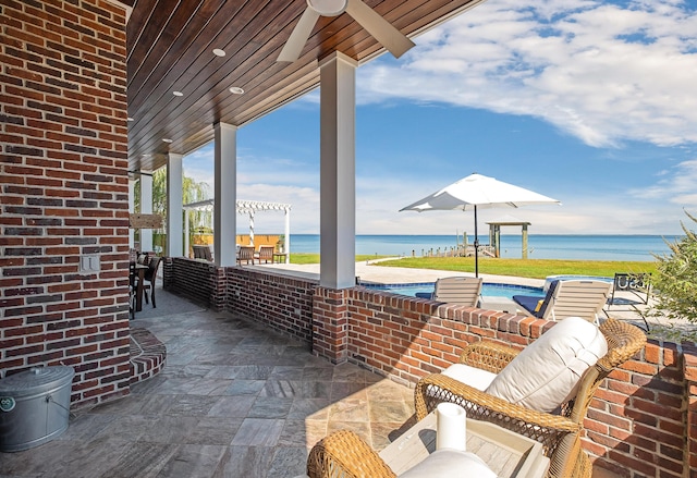 view of patio with a ceiling fan, an outdoor pool, and a water view