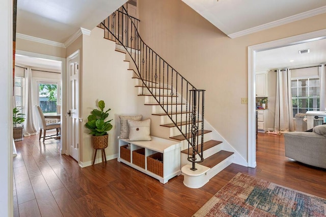 stairs featuring crown molding, baseboards, wood finished floors, and visible vents